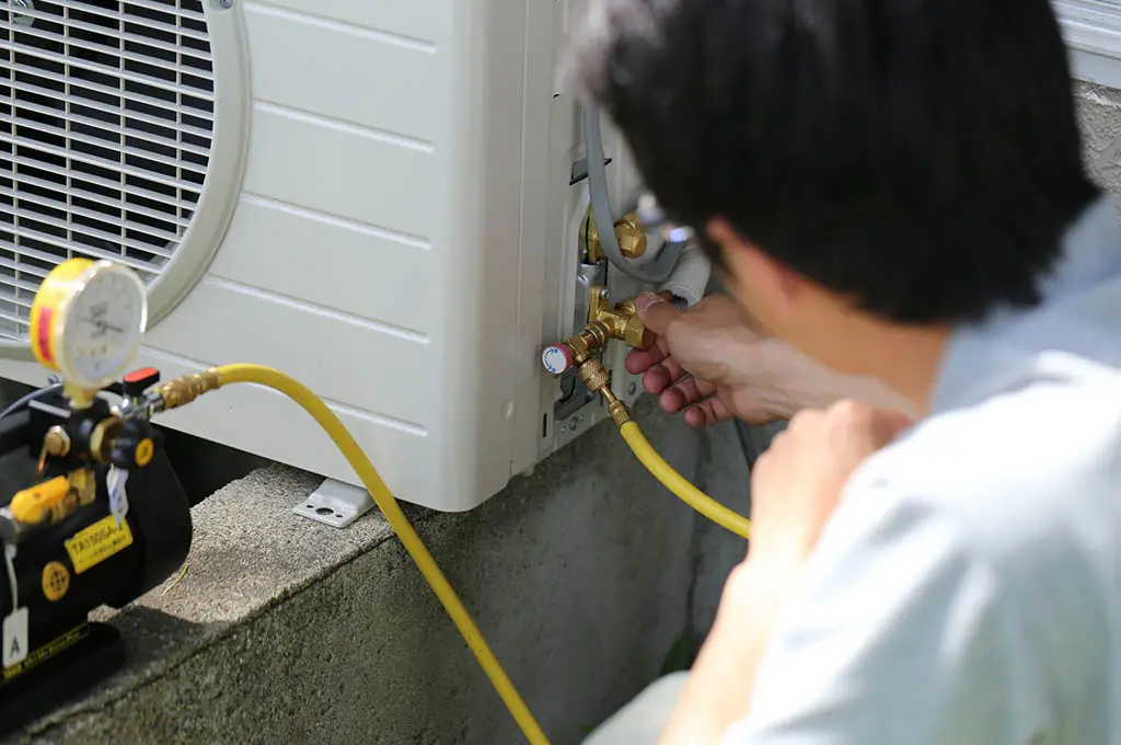 Immagine di un uomo che fa manutenzione ad una pompa di calore